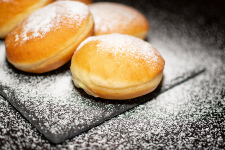 German Krapfen with drizzling glazed sprinkles in black elegant backgroundの写真素材