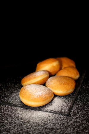 German Krapfen with drizzling glazed sprinkles in black elegant background