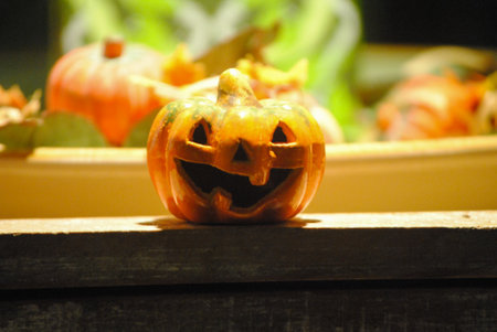 Small smiling pumpkin in shadows with others in background as Halloween timeの写真素材