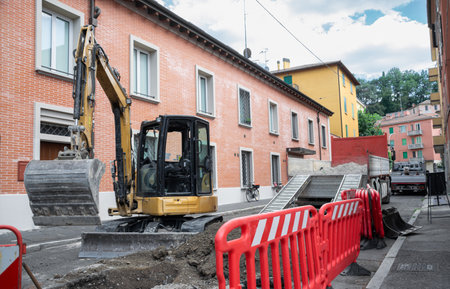 Construction Area with excavator deployed and red safety barriers along street