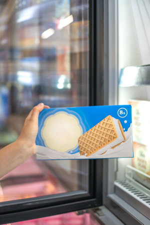 Hand taking Ice Cream stocked on supermarket for selling and ready for consumptionの写真素材
