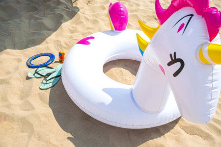 Close up view image of Fun inflatable pony float with flip flops on beach sandの写真素材