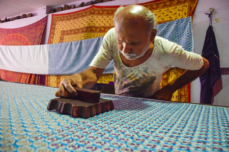 Artisan stamping patterns in ink on traditional Indian textiles as colorful sariの写真素材