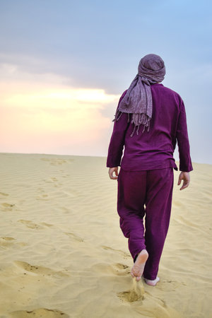 Back view Mature Masculine model walking through desert at sunset calmの写真素材