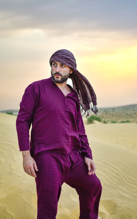 Turned view Mature Masculine model with beard posing in desert at sunset calmの写真素材