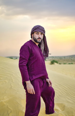 Turned view Mature Masculine model with beard posing in desert at sunset calmの写真素材