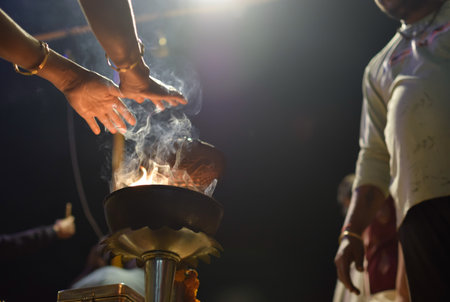 Outstretched hands of indian people praying over flame of Aarti ceremony lampの写真素材