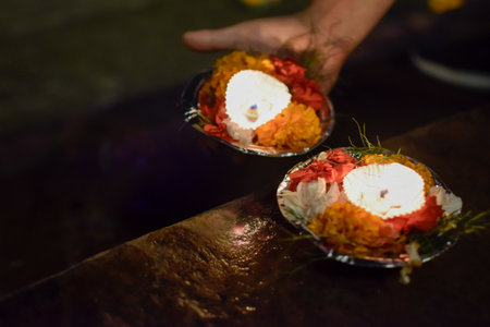 Indian Hand releasing offering with candles and flowers on bank of Ganges