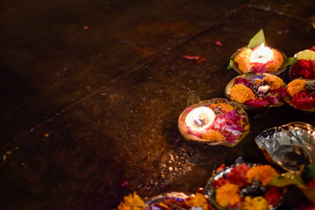Colored Dishes with candles and flowers in offering floating on bank of Gangesの写真素材