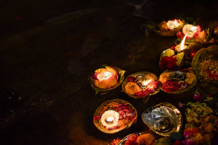 Colored Dishes with candles and flowers in offering floating on bank of Gangesの写真素材