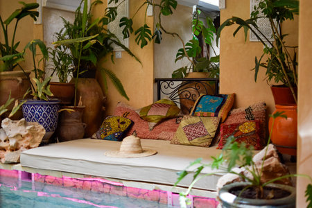 Balinese Bed with colorful cushions, decorative plants, a hat and swimming pool