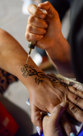 Hands holding while painting a henna tattoo typical of Arab and Hindu culturesの写真素材