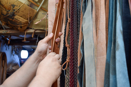 Handmade leather belts hung in souk shop with hands selecting at Marrakech