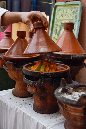Hand lifting a tagine while cooking with delicious typical Marrakesh food insideの写真素材