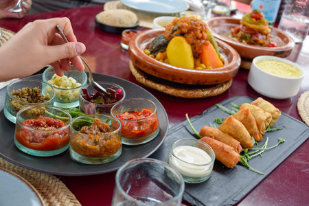 Hand serving food in table with Moroccan cuisine dishes as cous cous and tajinの写真素材