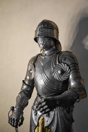 Front view of medieval shiny armor with details and white wall in background