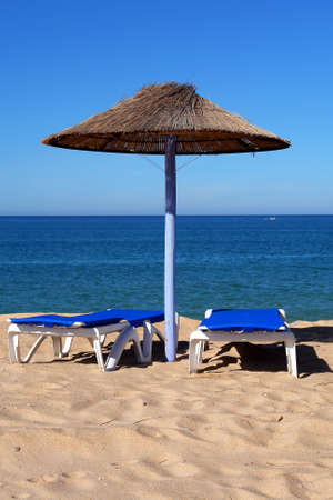 Parasol and sun loungers on the beach sandの写真素材