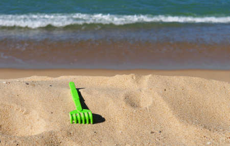 Child green toy on the sand beach の写真素材
