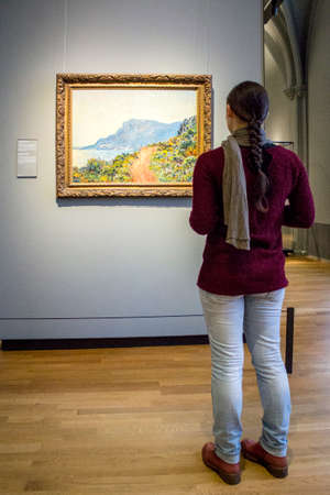 AMSTERDAM, NETHERLANDS - FEBRUARY 08: Visitor at Rijksmuseum admiring La Corniche near Monaco, by Claude Monet, on February 08, 2015 in Amsterdam. The Rijksmuseum is located at the Museum Square, and first opened its doors in 1885.のeditorial素材