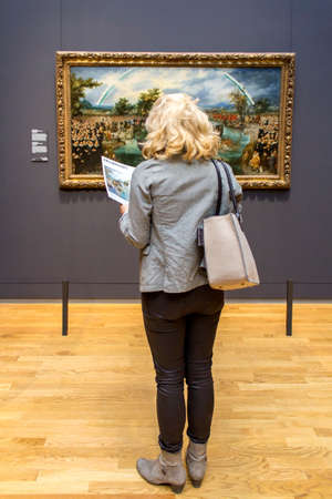 AMSTERDAM, NETHERLANDS - FEBRUARY 08: Visitor at Rijksmuseum admiring Fishing for Souls, by Adriaen Pietersz, on February 08, 2015 in Amsterdam. The Rijksmuseum is located at the Museum Square, and first opened its doors in 1885.のeditorial素材