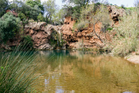 Beautiful waterfall with small lake in famous hidenn natural picnic rea called Pego do inferno Hells Pond near Tavira Algarve. Portugal.の写真素材
