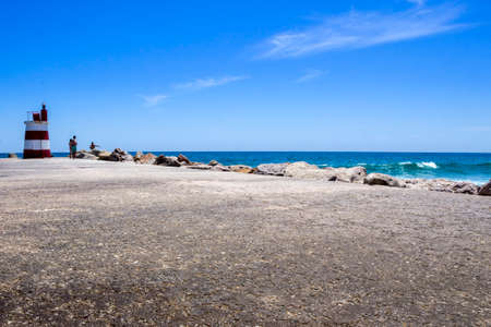 Ocean view and small lighthouse in the inlet jetty of Tavira Island Algarve Portugal.の写真素材