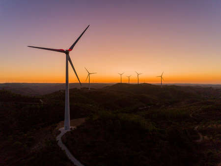 Aerial panoramic Wind farm turbines silhouette at sunset. Clean renewable energy power generating windmills. Algarve countryside. Portugal.の写真素材