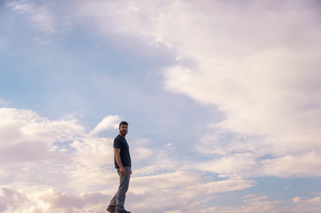 Young man walks through the sky on a beautiful sunsetの写真素材