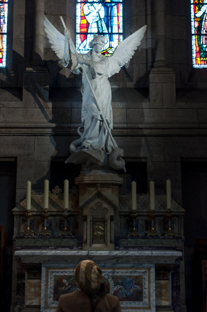 Back woman praying in church in front of the sculpture of the Angelのeditorial素材