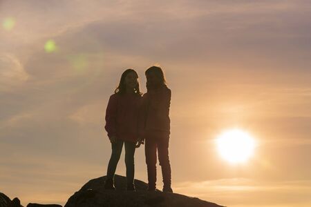 Girls playing at sunset on top of the mountainの写真素材