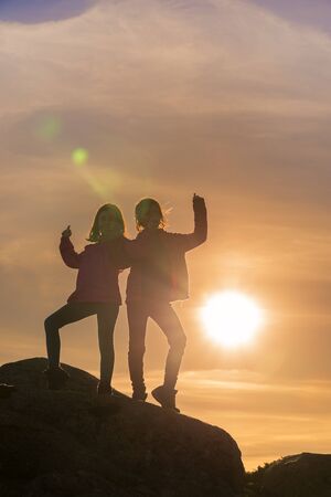 Girls playing at sunset on top of the mountainの写真素材