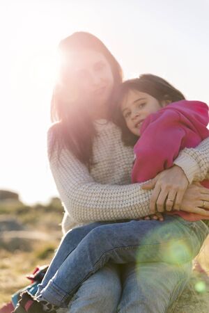 Portrait of mother and her daughter embracing and playing in the bright light of the sun, happy family.の写真素材