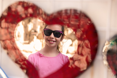 Funny portrait of little girl reflected in a mirror of heartの写真素材