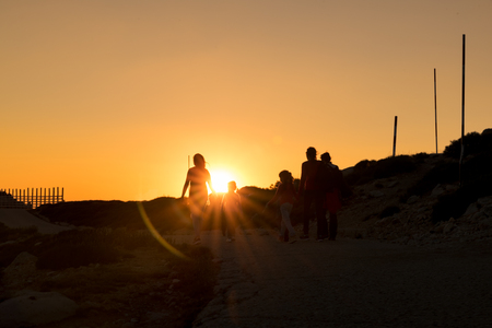 Silhouettes of hikers enjoying sunset view from top of a mountainの写真素材