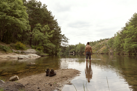 Hiker takes a refreshing break in the mountain lakeの写真素材