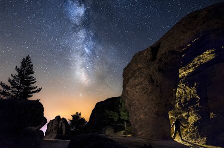 Silhouette of a man  in the night exploring a cave in the mountain with a torch under an amazing the milky way. Soria, Spainの写真素材