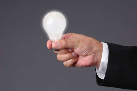 Light bulb shinning at hand with neutral background