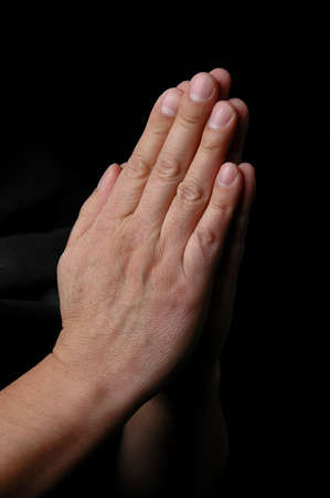 Hands in prayer on dark background