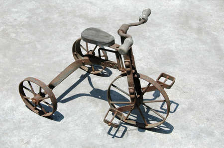 Antique Tricycle with sharp shadow seating on a concrete surfaceの写真素材