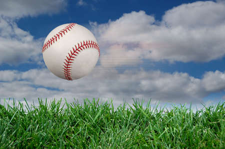 Baseball after impact with grass and cloudsの写真素材