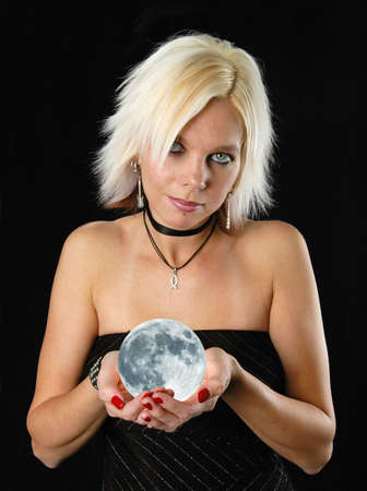 Beautiful blond girl holdind the moon on a black backgroundの写真素材