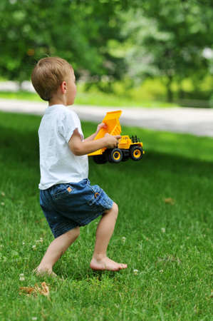Little boy running with track toy in the parkの写真素材