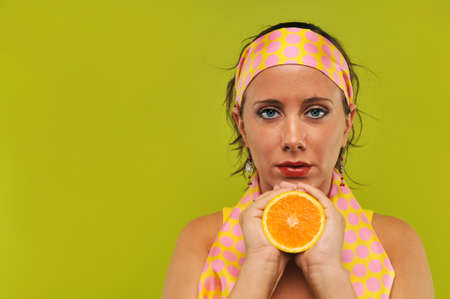 Brunette holding orange against a green backgroundの写真素材