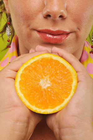 Brunette holding orange against a green backgroundの写真素材
