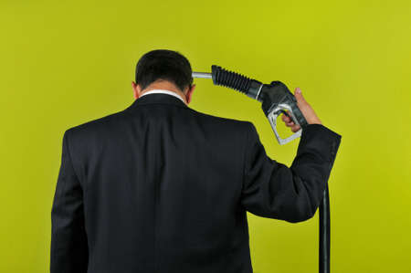 Businessman committing suicide with a gas nuzzle isolated on a green backgroundの写真素材