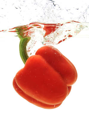 Red pepper dropped in the water isolated against a white backgroundの写真素材