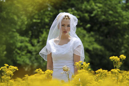 Bride in a yellow flowers field on a sunny dayの写真素材