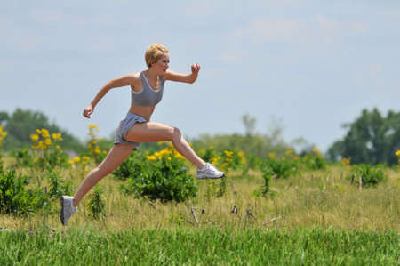Young woman running on a dirt road outdoors on a sunny dayの写真素材