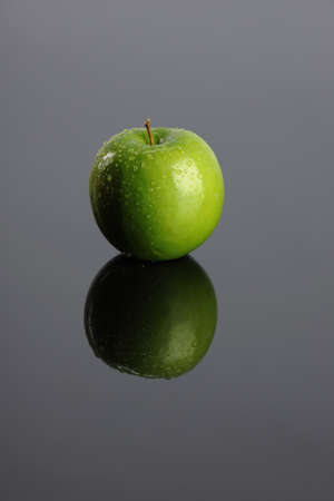 Green apple with reflection on a gray backgroundの写真素材