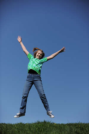 Young Girl Jumping on a sunny day against a blue skyの写真素材